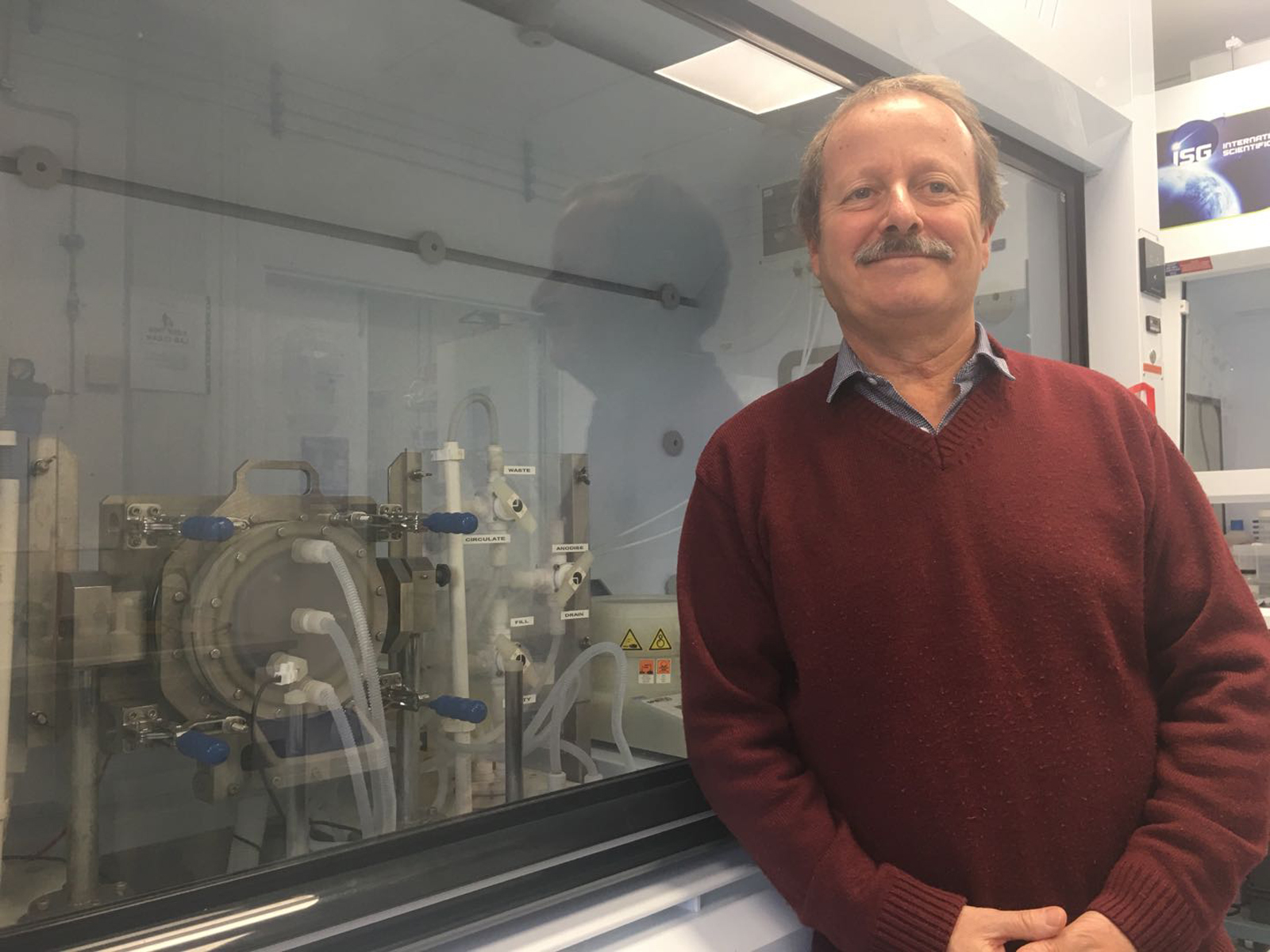 Professor Canham stands in front of a fume hood smiling at the camera Professor Canham stands in front of a fume hood smiling at the camera