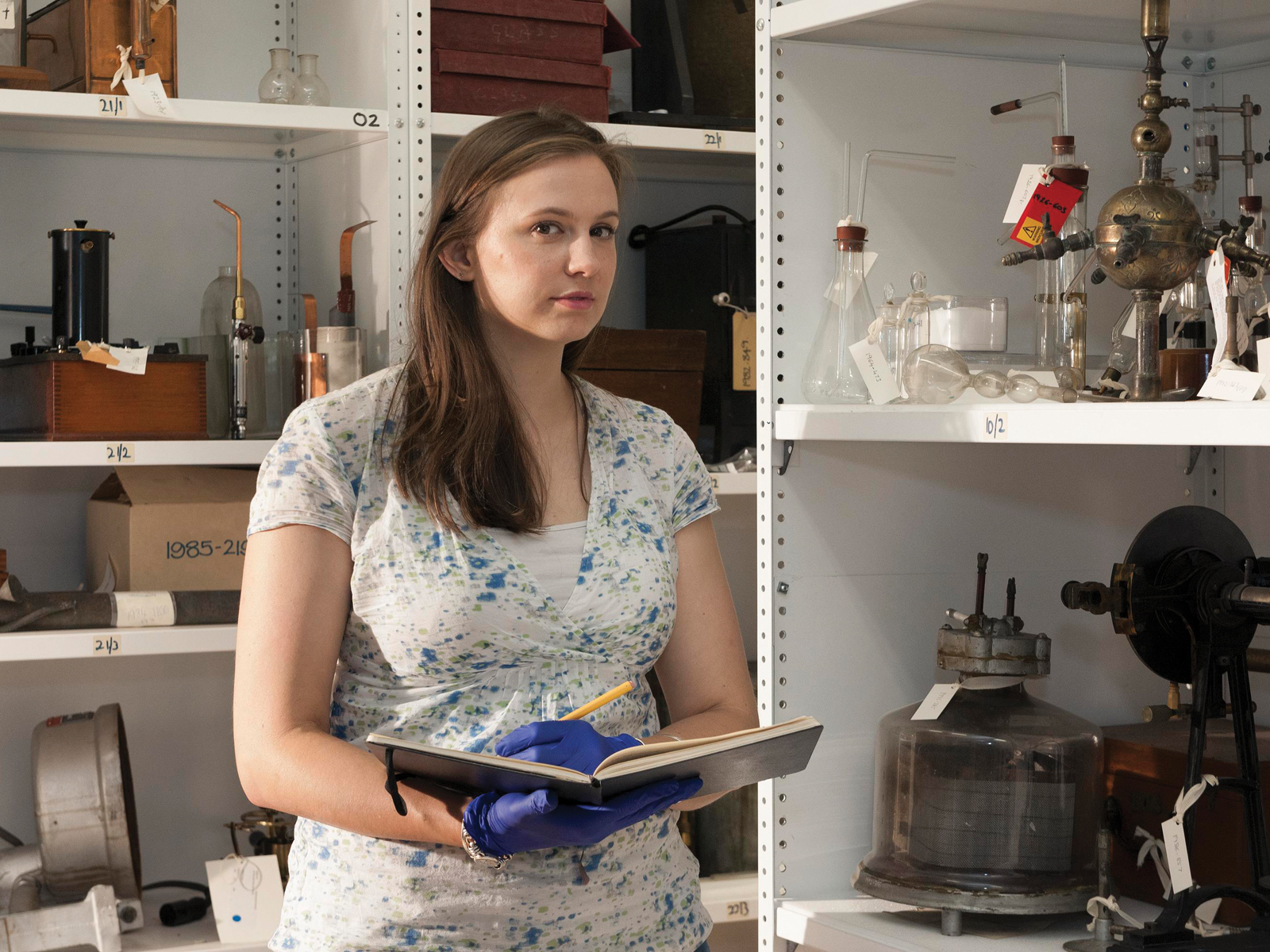 Sophie Waring surrounded by historical glassware and other scientific equipment Sophie Waring surrounded by historical glassware and other scientific equipment