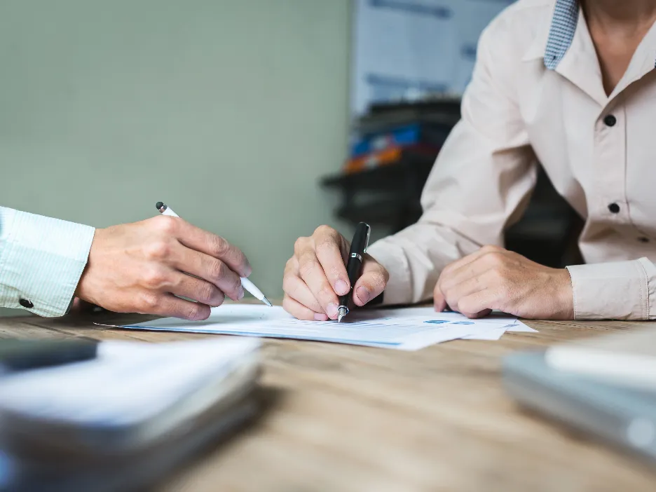 Two people working together on a document around a table