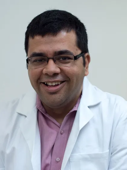Professor Sarbajit Banerjee wearing glasses and lab coat, smling at the camera