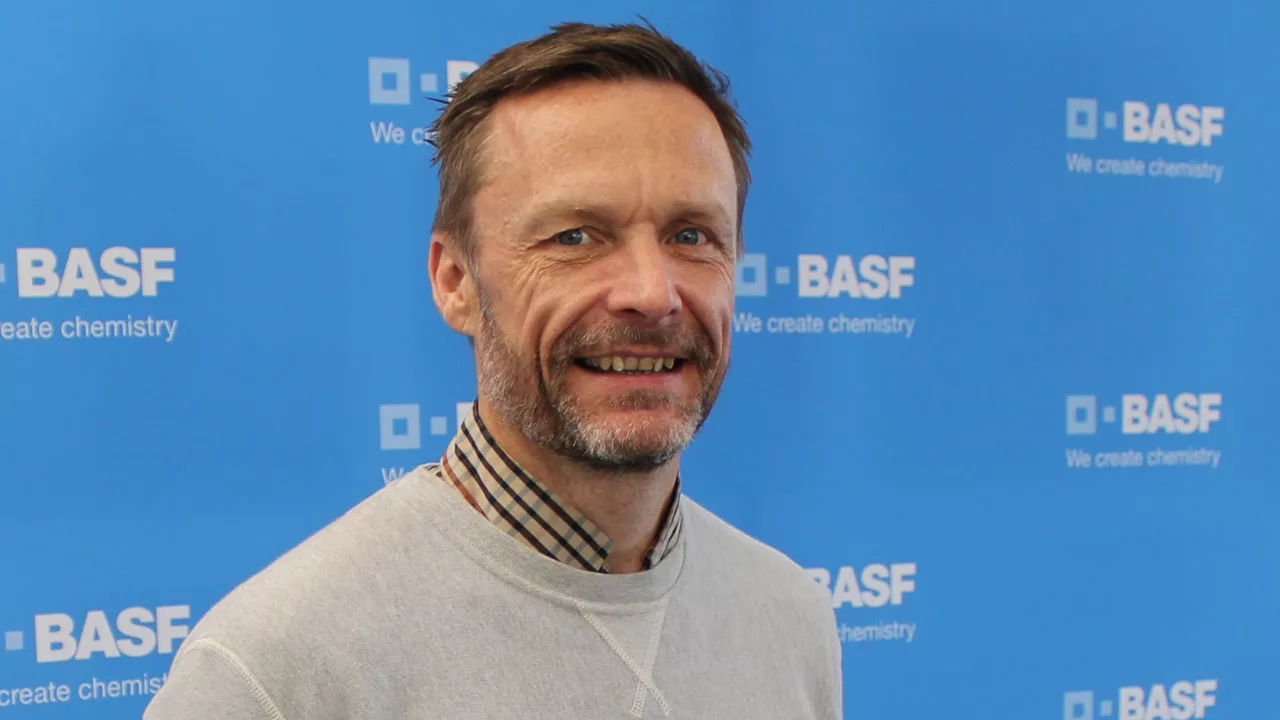 A portrait picture of Tony Heslop in front of a sky blue background with BASF logos all over. A portrait picture of Tony Heslop in front of a sky blue background with BASF logos all over.