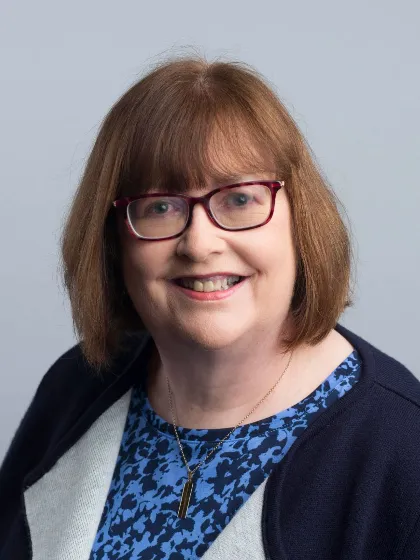a woman wearing glasses and a blue and black sweater