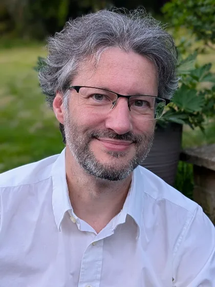 Professor Igor Larrosa wearing white shirt and glasses smiling for camera