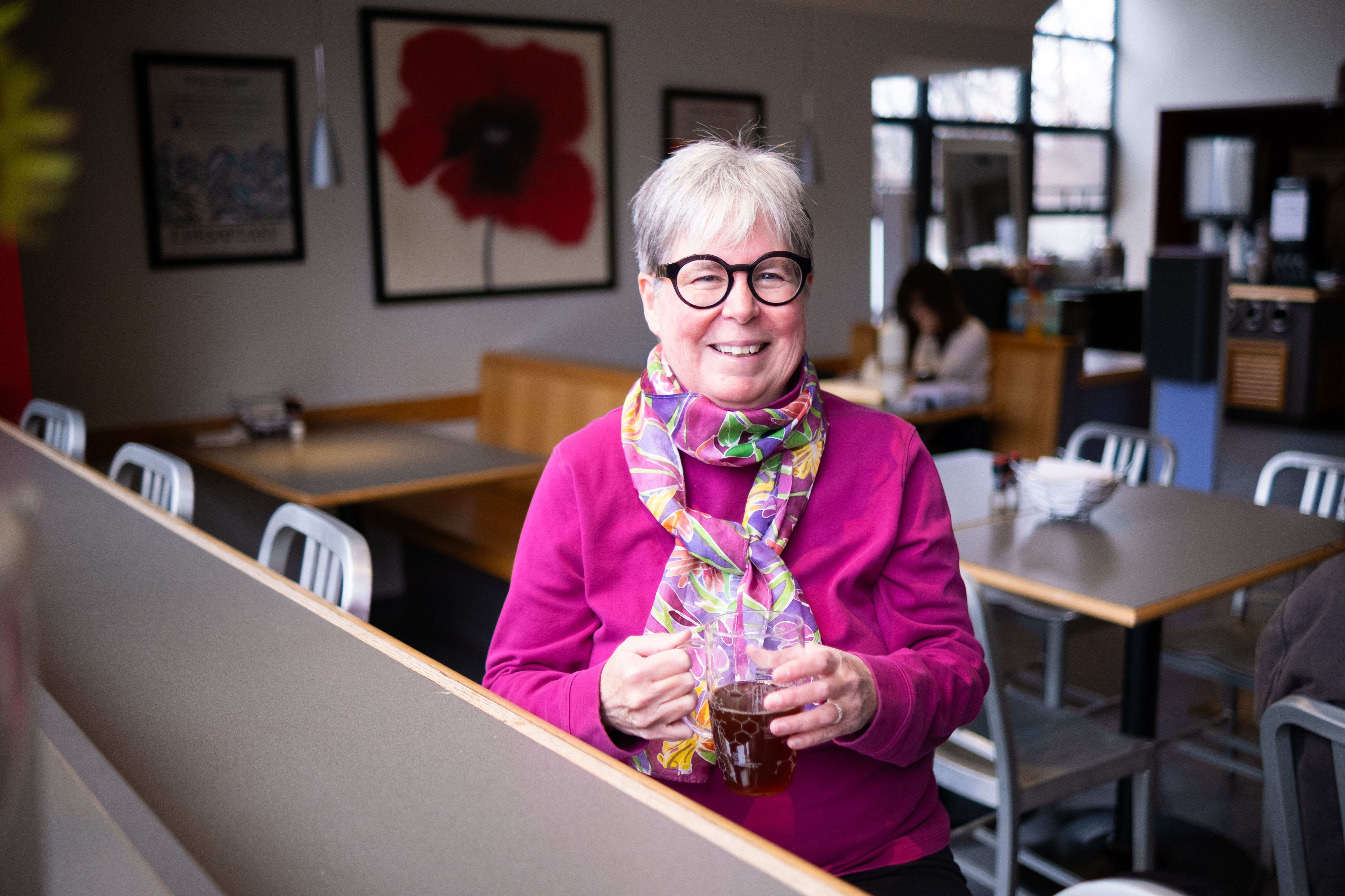 A smiling Dr Michelle Francl holds a glass cup of tea at an empty cafe A smiling Dr Michelle Francl holds a glass cup of tea at an empty cafe