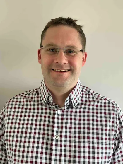 Professor Thomas Penfoldwearing glasses and checked shirt smiling for the camera